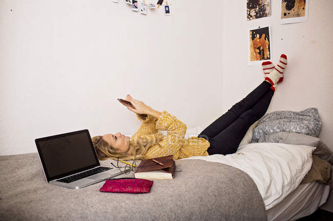 Mujer usando el teléfono mientras descansa en casa - foto de stock