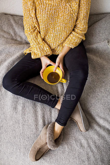 Mulher segurando xícara de café enquanto descansa na cama — Fotografia de Stock