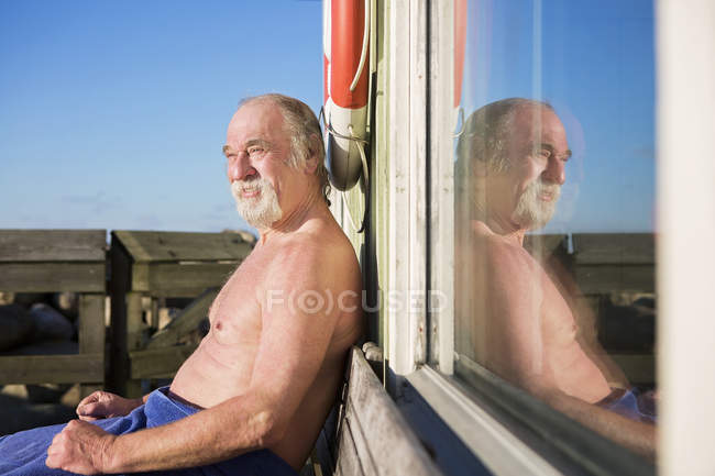 Homme assis sur le banc réfléchissant dans la fenêtre — Photo de stock