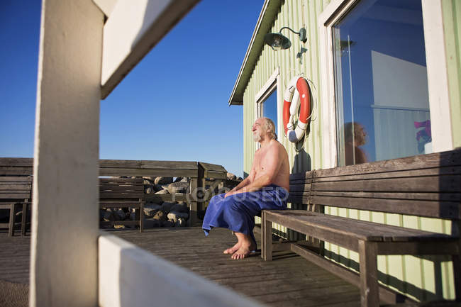 Man wrapped in towel sitting on bench — Stock Photo