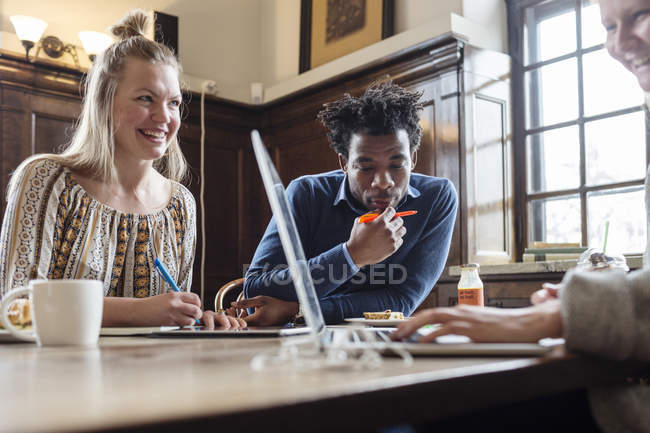 Amigos trabalhando ao usar laptop — Fotografia de Stock