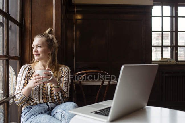Усміхнена жінка сидить у кафе — стокове фото