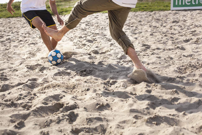 Hommes jouant au football à la plage — Photo de stock