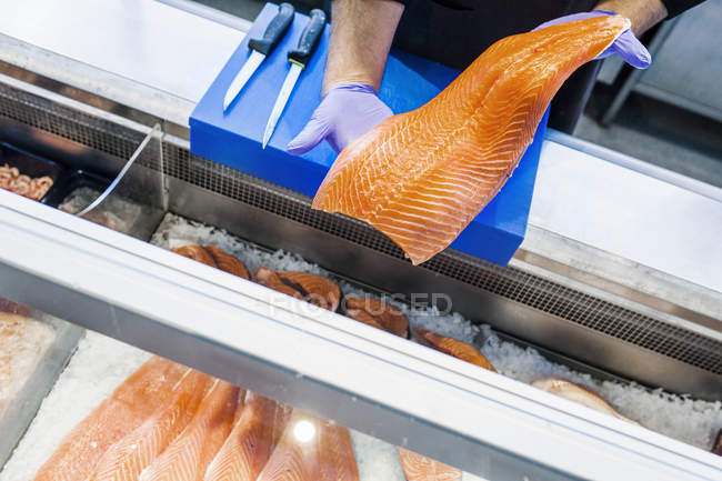 Vendor holding salmon at supermarket — Stock Photo