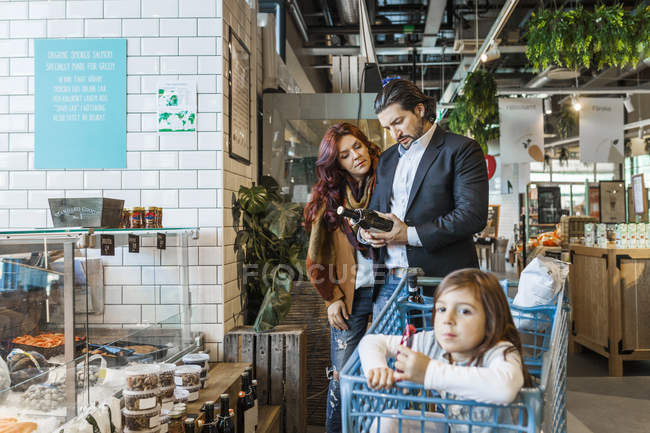 Mädchen sitzt mit Eltern im Einkaufswagen — Stockfoto
