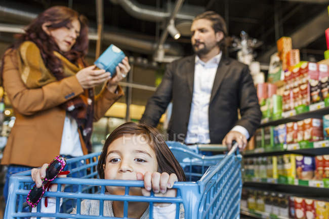 Mädchen sitzt mit Eltern im Einkaufswagen — Stockfoto