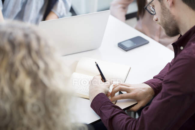 Empresário escrevendo em livro em reunião — Fotografia de Stock