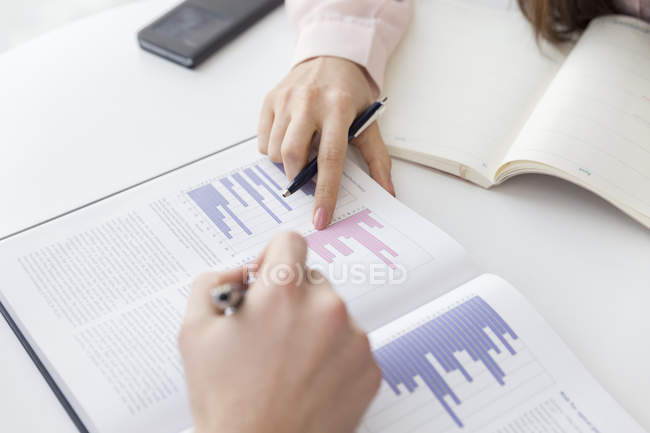 Hands pointing at graphs in meeting — Stock Photo