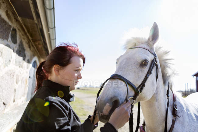 Donna che tiene la briglia mentre guarda il cavallo — Foto stock