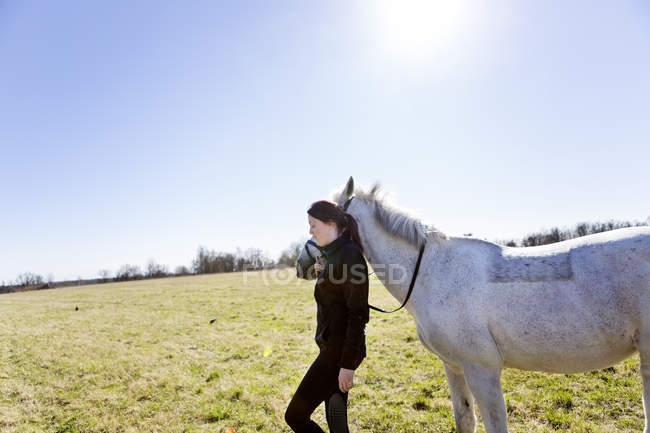 Donna che cammina con cavallo sul campo — Foto stock