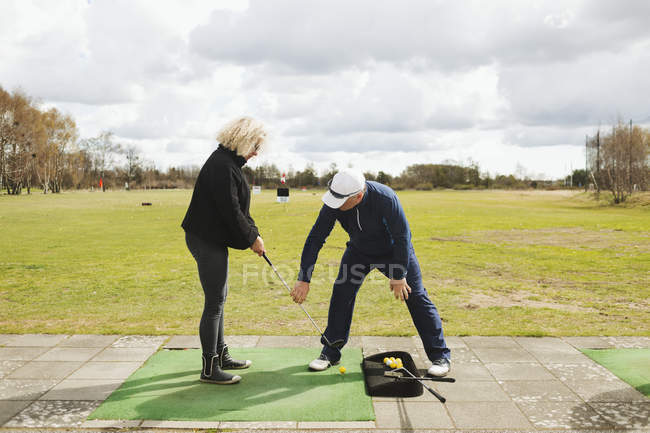 Мужчина преподает гольф женщине — стоковое фото