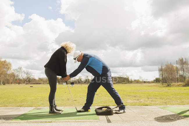 Hombre enseñando amigo a jugar al golf - foto de stock