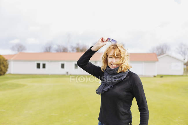 Mujer quitando gafas de sol en el campo de golf - foto de stock