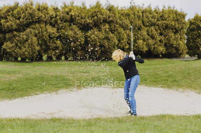 Femme jouant au golf sur le terrain — Photo de stock