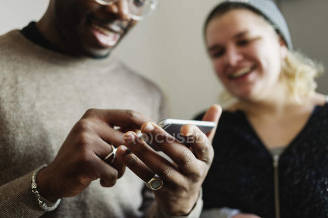 Amigos felices usando el teléfono inteligente - foto de stock