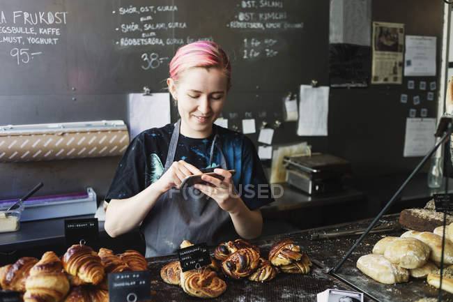 Smiling owner photographing breads — Stock Photo