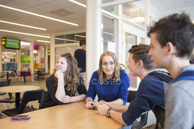 Schoolchildren sitting at table in corridor — Stock Photo