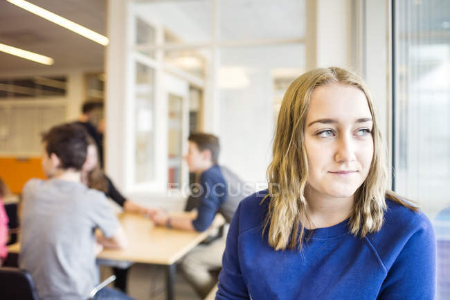 Retrato de colegiala mirando por la ventana - foto de stock