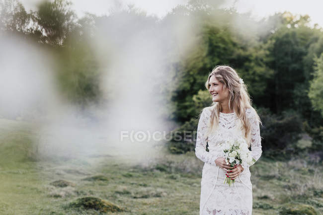 Noiva segurando buquê na floresta — Fotografia de Stock