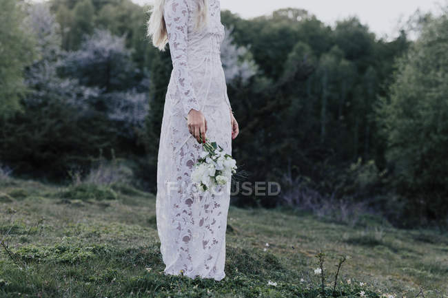 Noiva segurando buquê na floresta — Fotografia de Stock