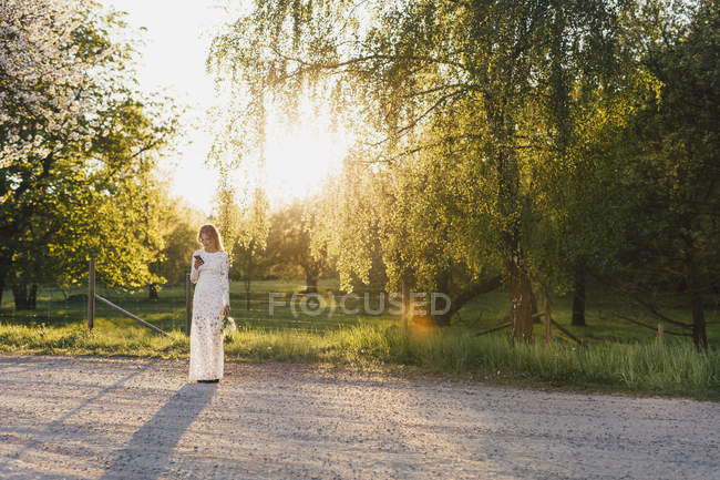 Braut mit Blumenstrauß und Smartphone — Stockfoto