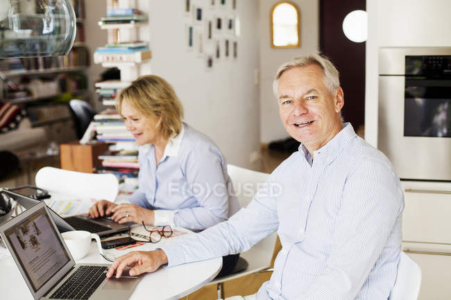 Hombre con mujer usando computadoras portátiles - foto de stock