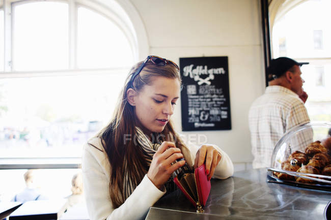 Mujer pagando en el mostrador de pago en la cafetería - foto de stock