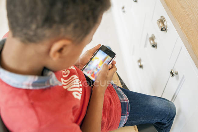Garçon jouer à des jeux sur téléphone intelligent — Photo de stock
