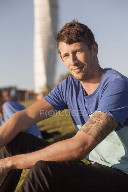 Усміхнений чоловік сидить у парку — стокове фото