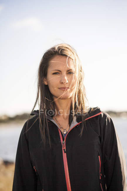 Donna in giacca in piedi vicino al lago — Foto stock