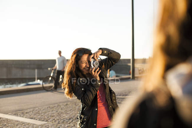 Счастливая женщина фотографирует друга — стоковое фото