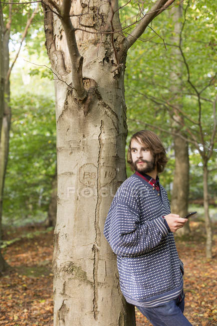 Homme appuyé sur l'arbre dans la forêt — Photo de stock