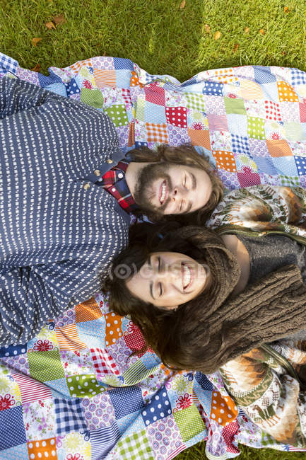Casal feliz deitado no cobertor piquenique — Fotografia de Stock