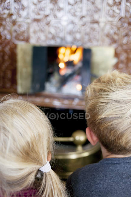 Niño y niña mirando a la chimenea - foto de stock