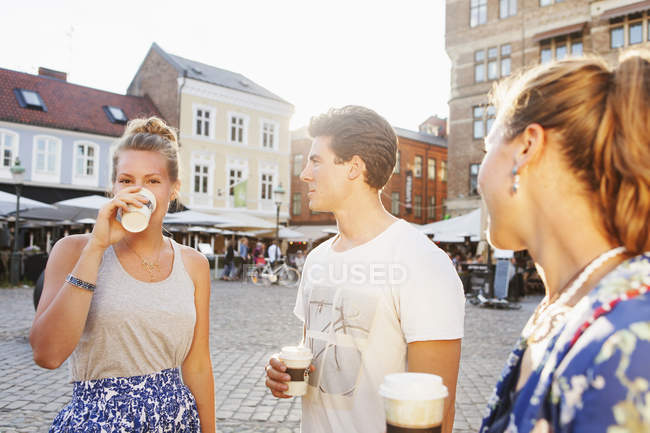 Friends looking at woman drinking coffee — Stock Photo