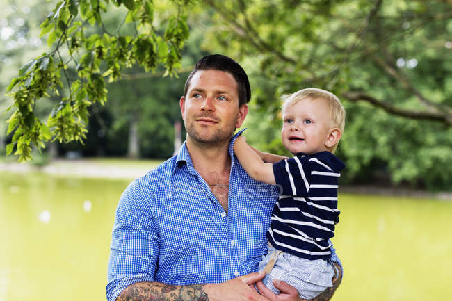 Joven y su hijo en el parque - foto de stock