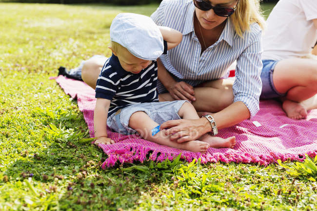 Mãe colocando bandagem na perna filhos — Fotografia de Stock