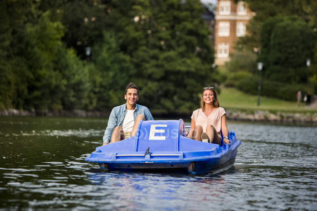 Happy friends pedal boating — Stock Photo