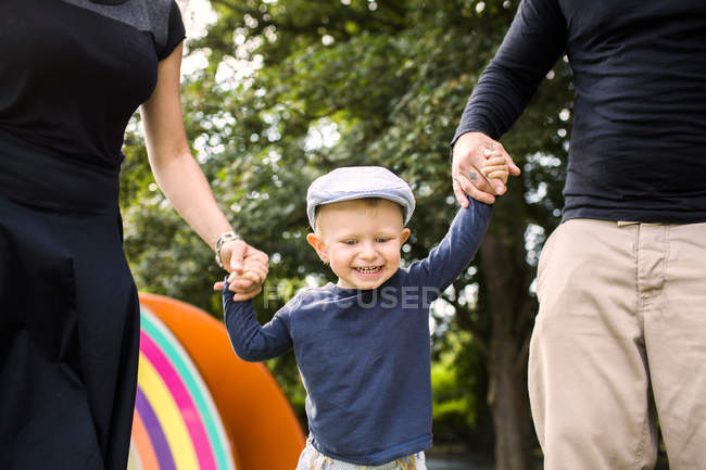 Madre y padre sosteniendo feliz hijo - foto de stock