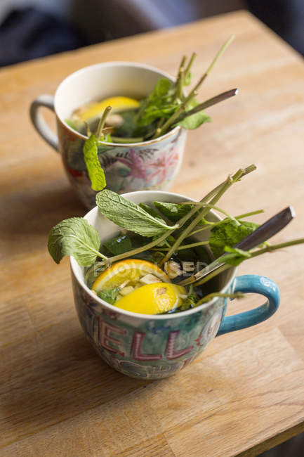 Deux tasses avec feuilles et citron — Photo de stock