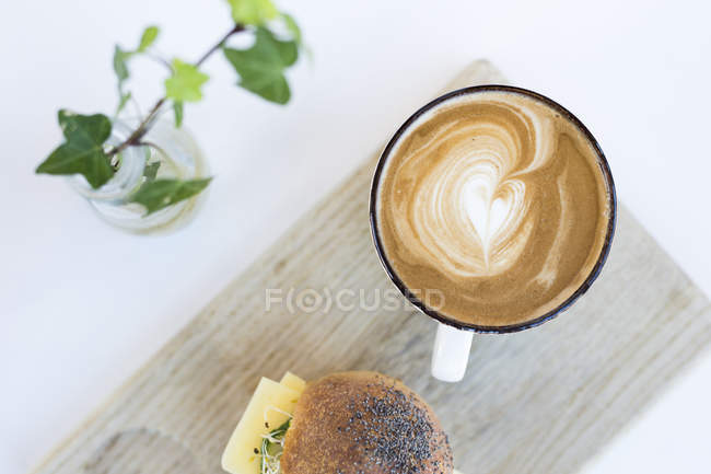 Cappuccino e panino sul tavolo — Foto stock