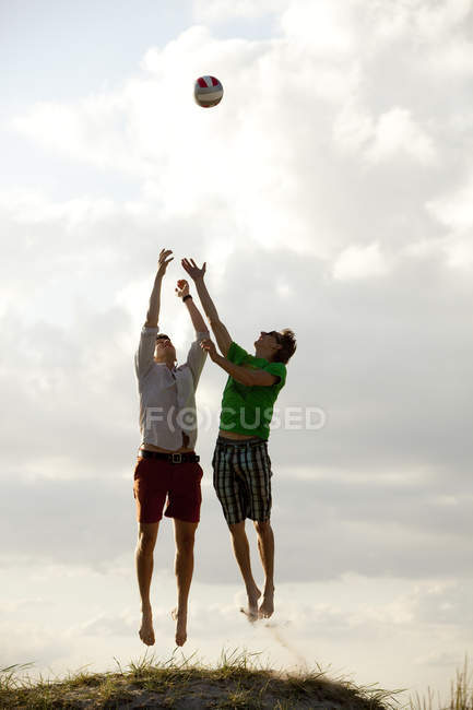 Молоді друзі чоловічої статі грають у волейбол — стокове фото