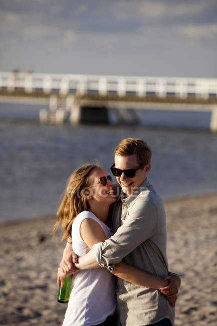 Улыбающаяся пара обнимается на пляже — стоковое фото