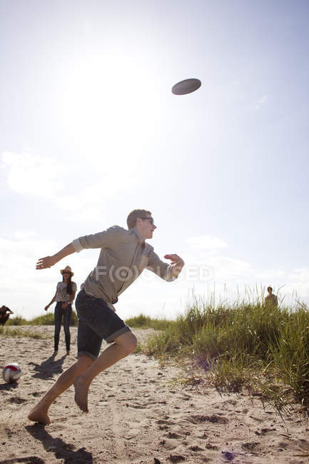 Verspielter junger Mann läuft am Strand — Stockfoto