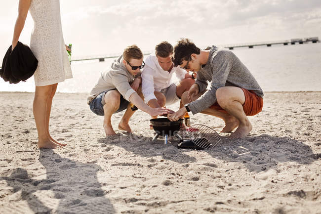 Giovani amici maschi illuminazione barbecue — Foto stock