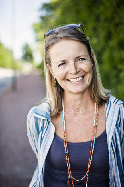 Mature woman smiling on sidewalk — Stock Photo