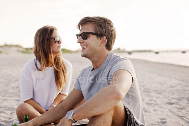 Homem sentado por amigo feminino na praia — Fotografia de Stock