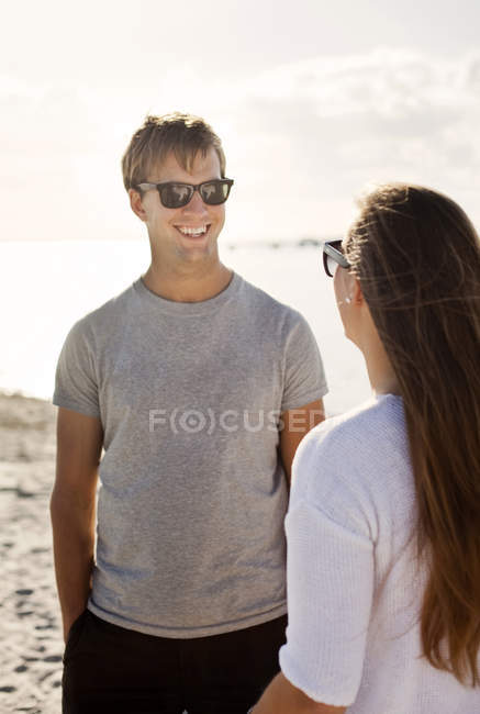 Homem falando com o amigo feminino na praia — Fotografia de Stock