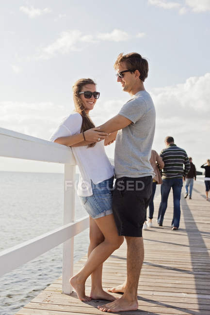 Paar steht am Brückengeländer über dem Meer — Stockfoto