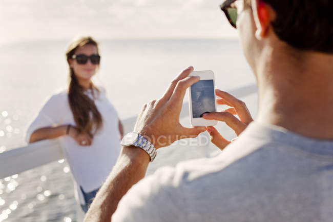 Mann fotografiert Freundin auf Pier — Stockfoto